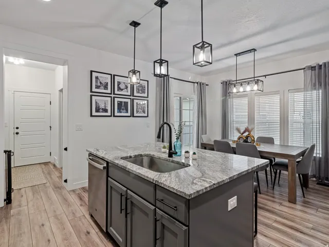 Kitchen island featuring a stainless steel sink, granite countertop, and dark cabinetry