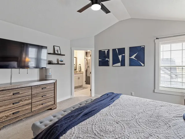 Vaulted ceiling with a ceiling fan, recessed window with blinds, and light-toned carpet flooring