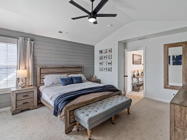 Carpeted room featuring a vaulted ceiling with a ceiling fan, a shiplap accent wall, and a window with blinds