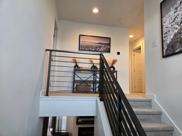 Carpeted staircase with contemporary metal railing, recessed lighting, and white trim