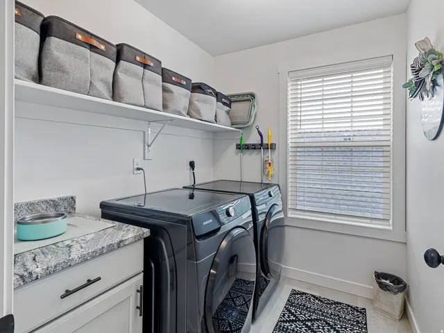 White cabinetry with dark hardware, stone-finish countertop, and white overhead shelving