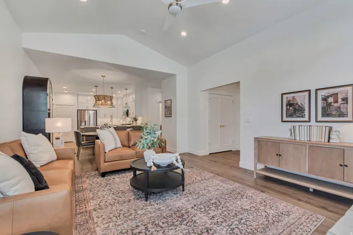 Vaulted ceiling with recessed lighting, wood-finish flooring, and white walls