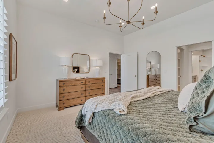 Vaulted ceiling with an industrial-style chandelier, arched doorway, recessed lighting, and soft carpet flooring