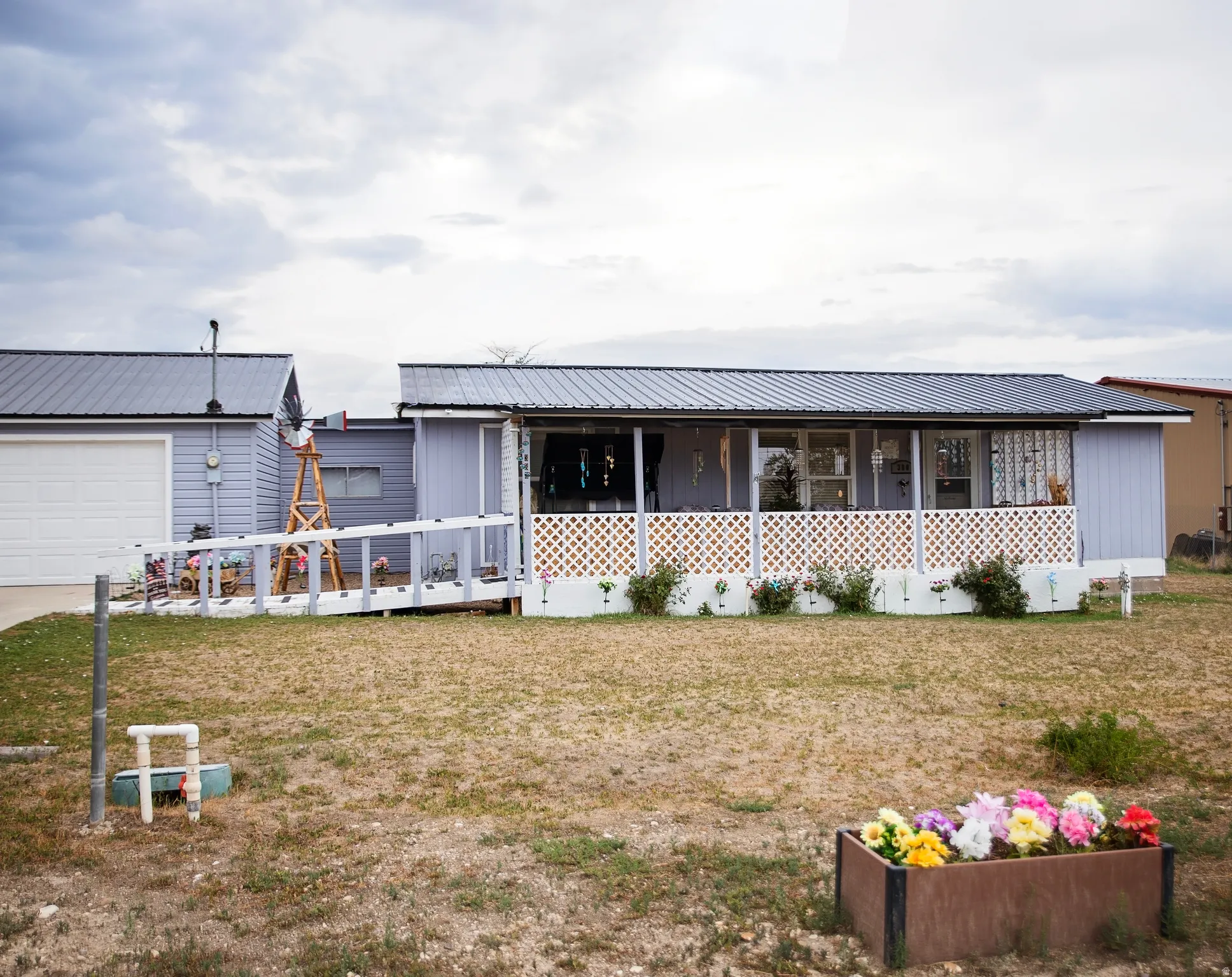 Property exterior featuring a screened porch, metal roofing, attached garage, and a wood ramp access