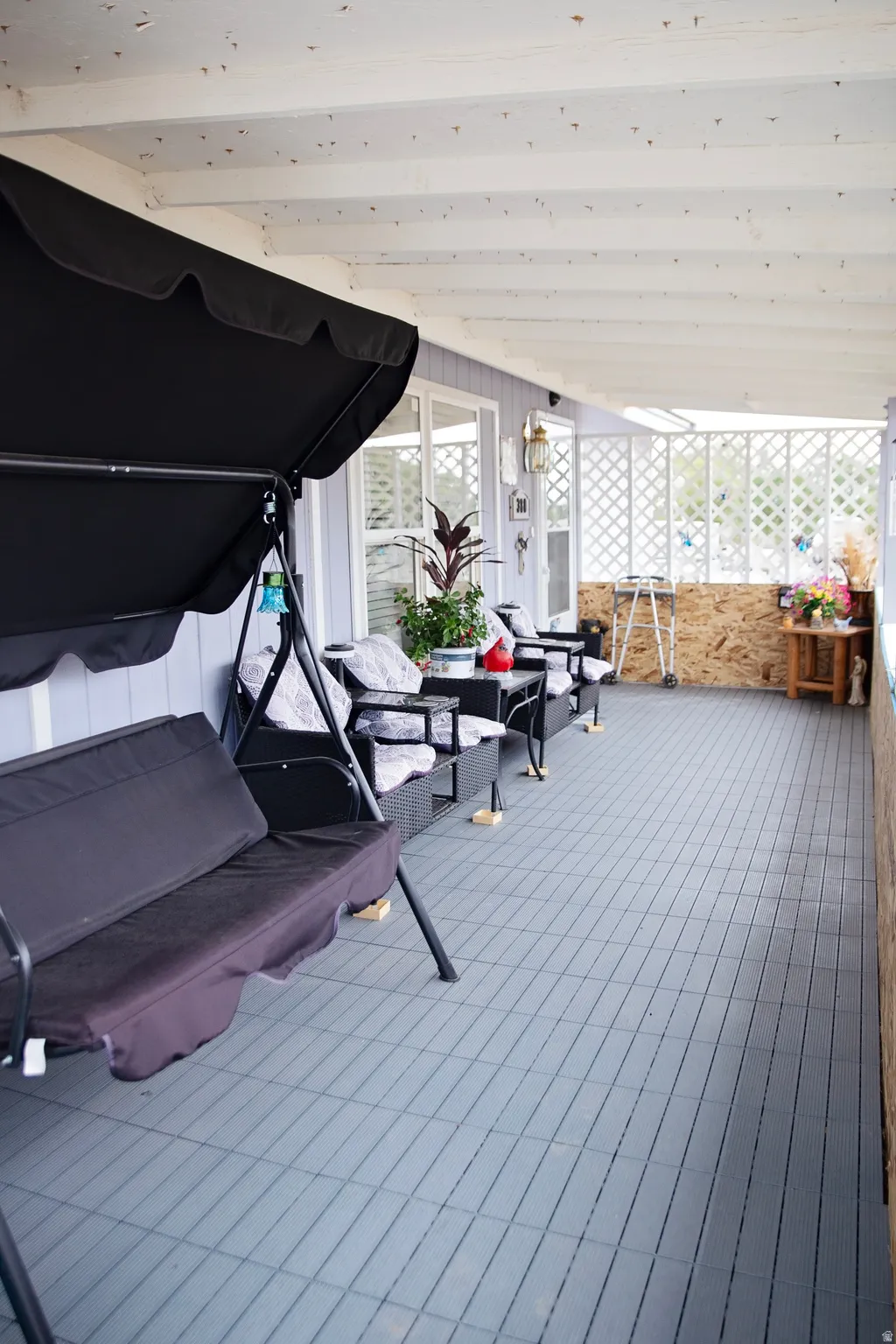 Covered patio featuring a slatted ceiling, windowed wall, and patterned tile flooring
