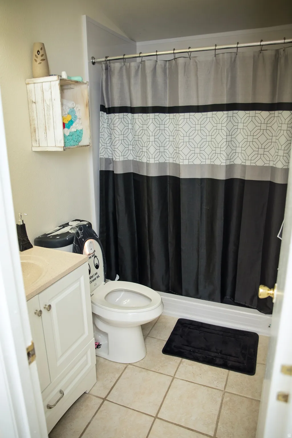White vanity with cabinet storage, beige countertop, and integrated sink
