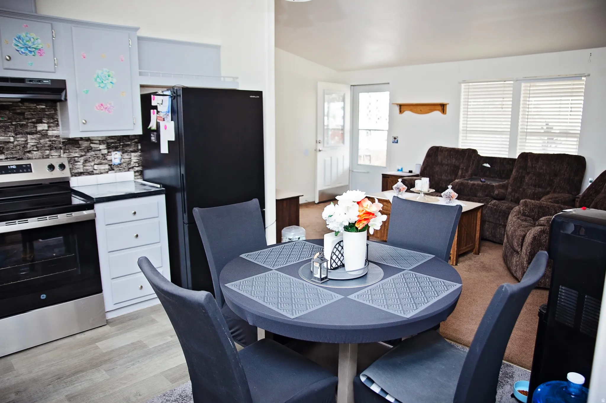 Kitchen area featuring light gray cabinetry, stainless steel range, and black refrigerator