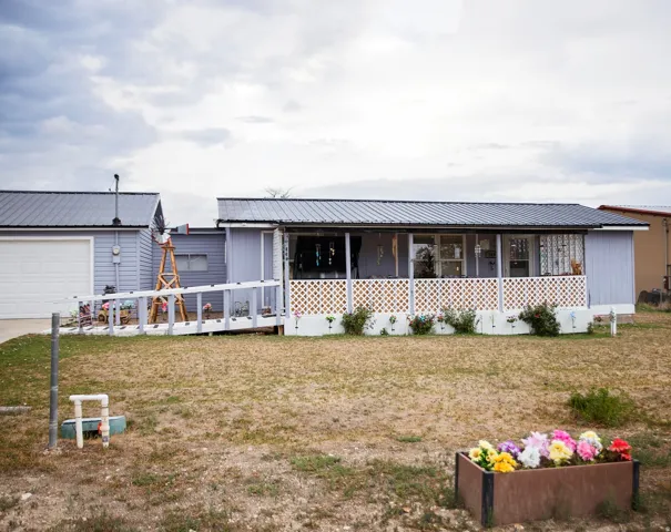 Property exterior featuring a screened porch, metal roofing, attached garage, and a wood ramp access