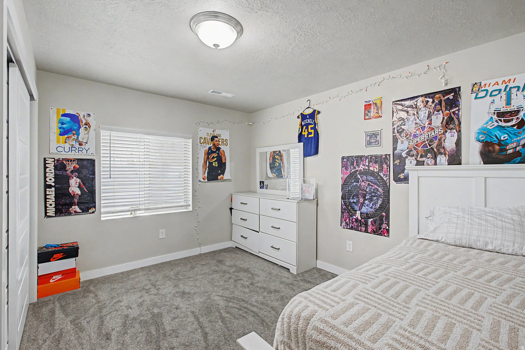Grey carpet flooring, white walls, built-in closet with bi-fold doors, white window blinds, and a semi-flush mount ceiling light fixture