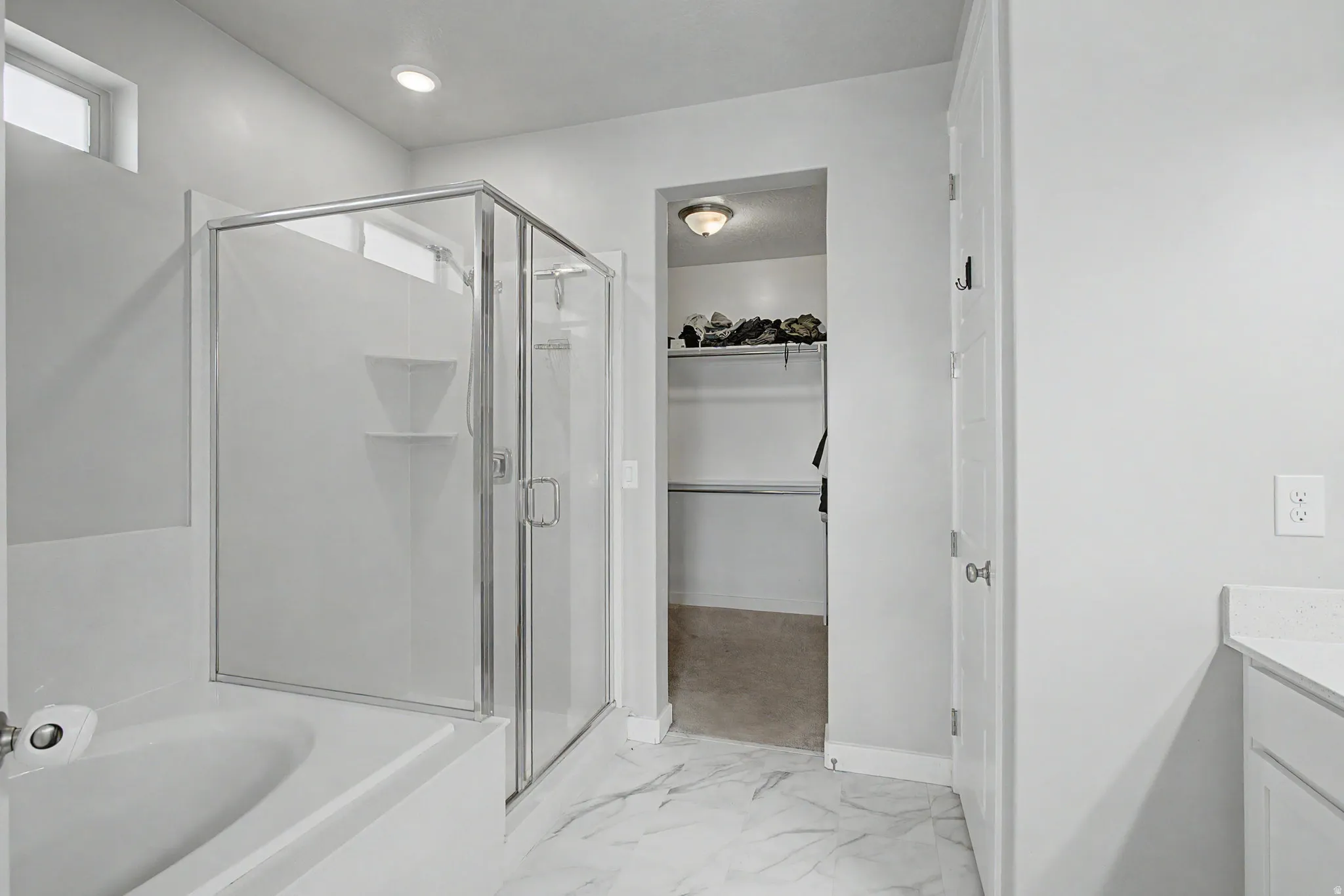 Full shower enclosure with glass doors, built-in tub, marble-patterned floor tiles, and recessed lighting