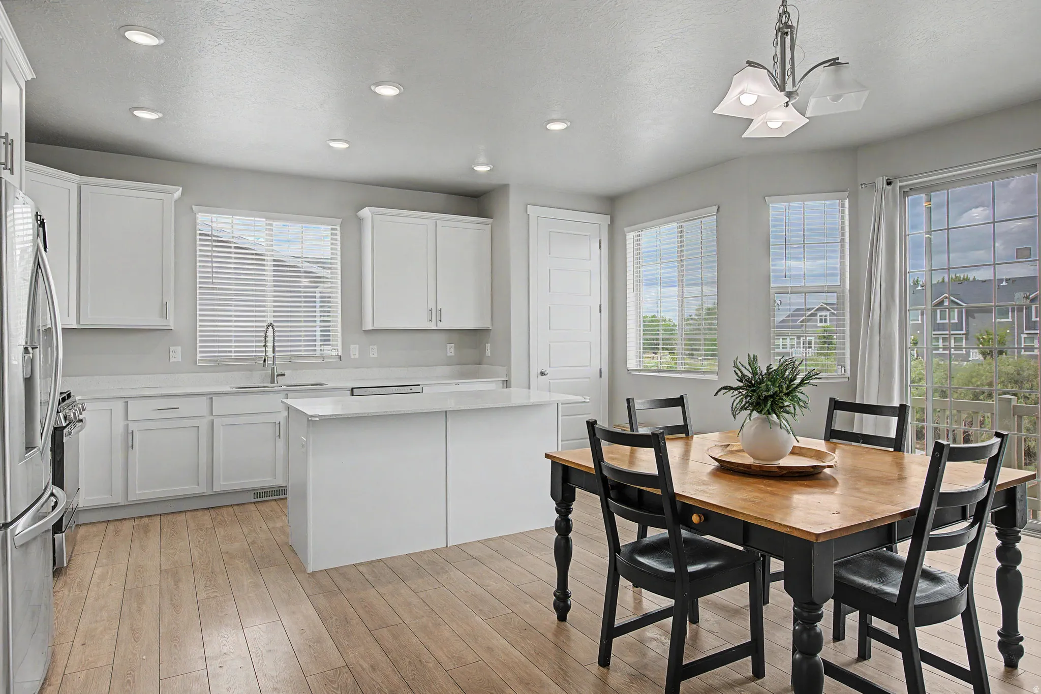 Bright kitchen featuring white cabinetry, a central island, wood-finish flooring, recessed lighting, and a sliding glass door