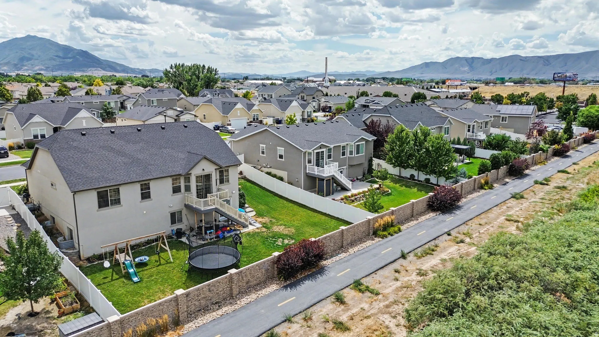 Rear exterior with a multi-level deck, fenced backyard, and a paved pathway bordering the property