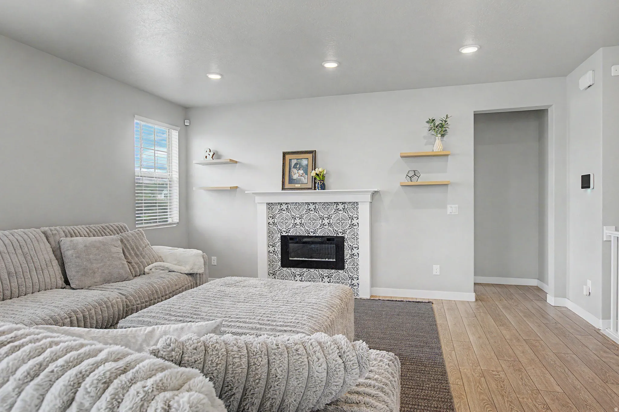 Living area featuring an electric fireplace with decorative tile surround and mantel, recessed lighting, wood-finish flooring, and natural light