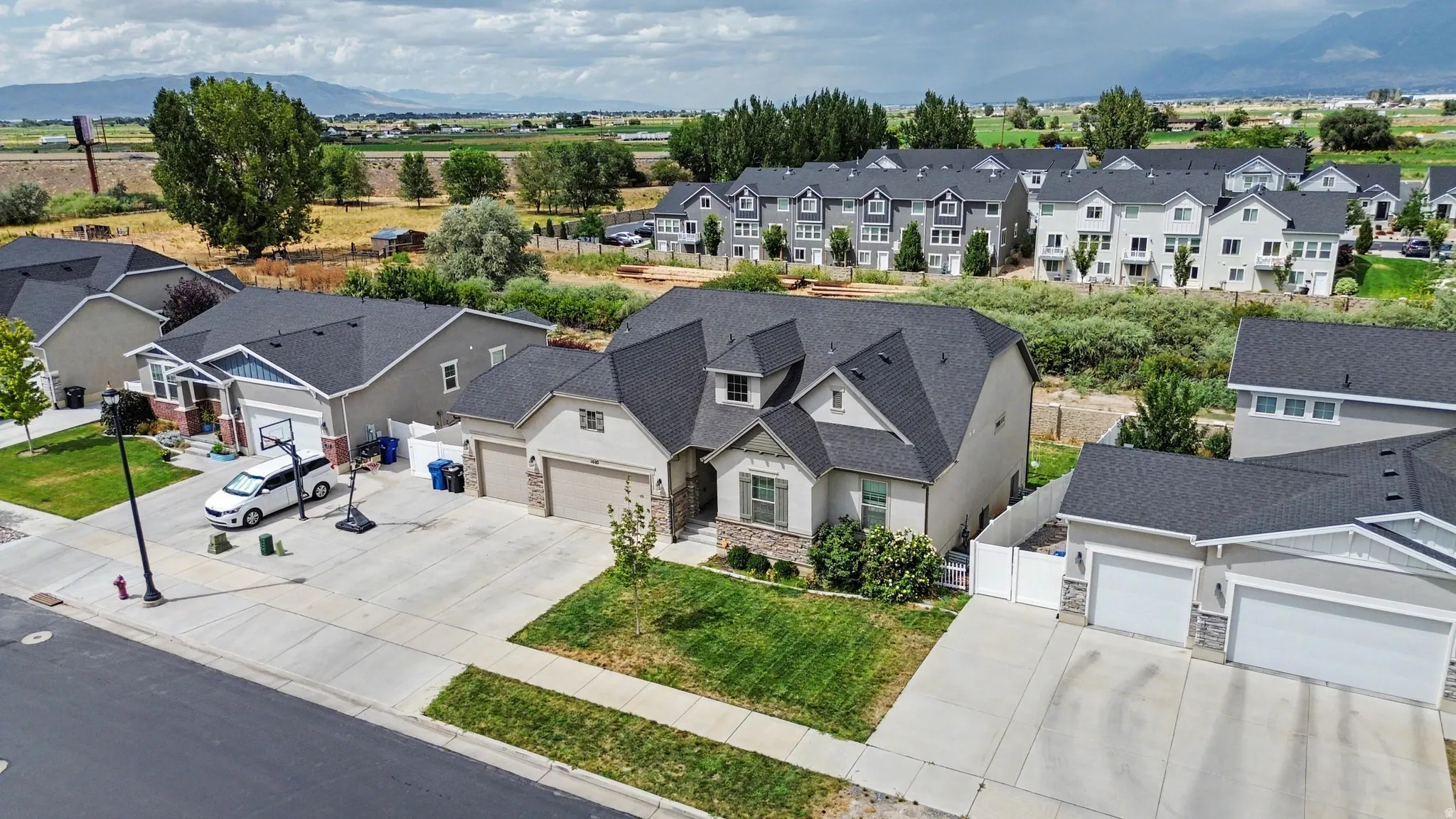 Exterior featuring a stone-clad facade, attached multi-car garage, and a manicured front lawn