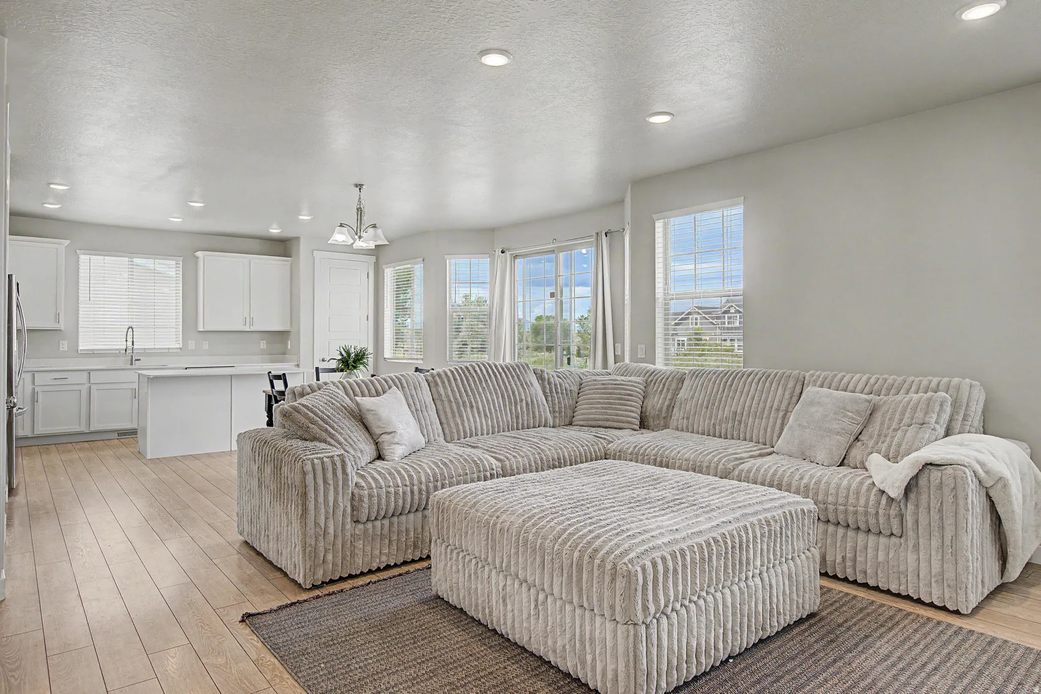 Open-concept living area featuring wood-finish flooring, recessed lighting, and ample natural light from multiple windows