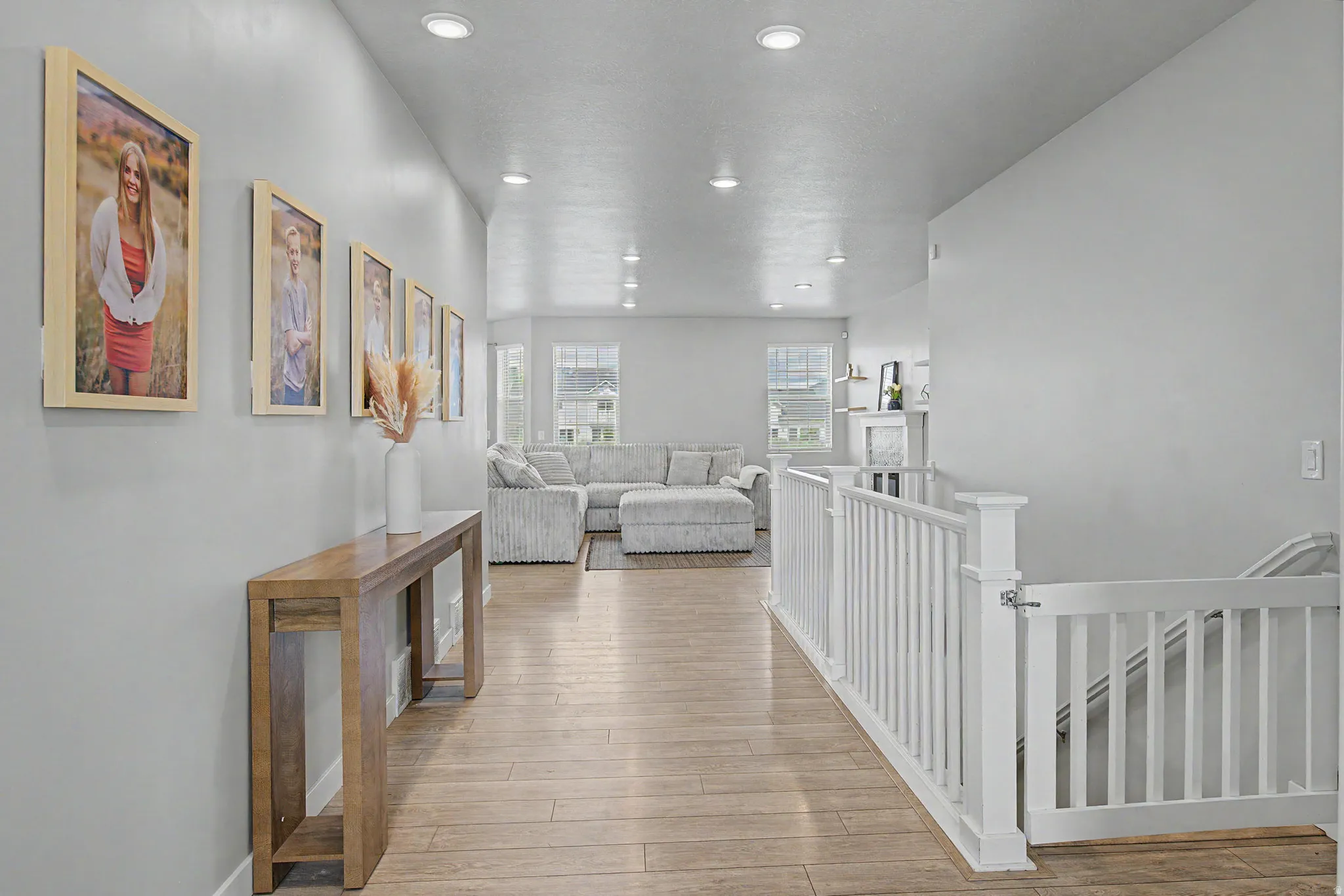 Recessed lighting, wood-finish flooring, white balustrade, multiple windows, light neutral wall color