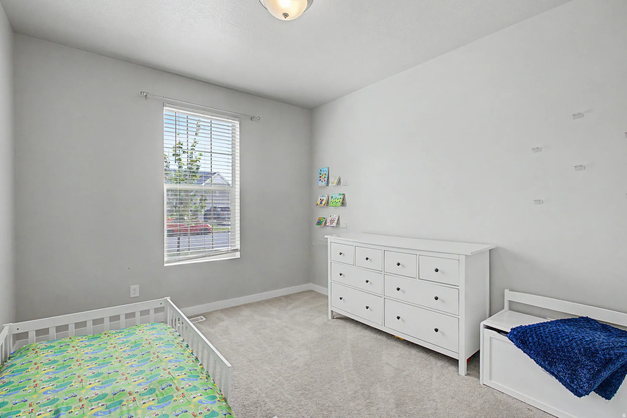 Light gray painted walls, light gray carpeting, and a single window with horizontal blinds