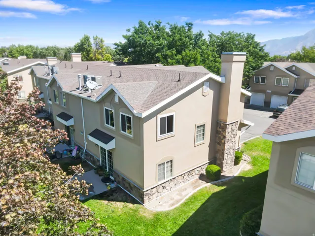 Stucco exterior with stone veneer accents, multi-pane windows, and a shingle roof