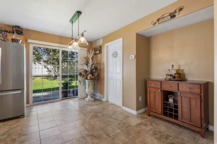 Ceramic tile flooring, sliding glass door, overhead lighting fixture, and a built-in wooden cabinet with storage