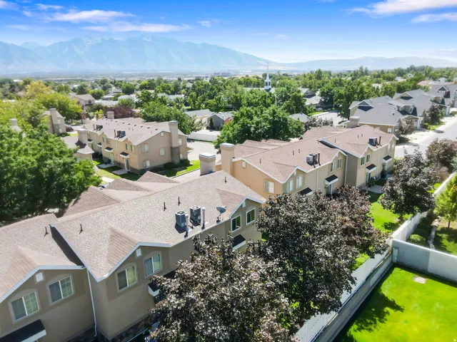 Townhome community with mountain backdrop, multiple residential buildings, landscaped grounds, and paved roadways