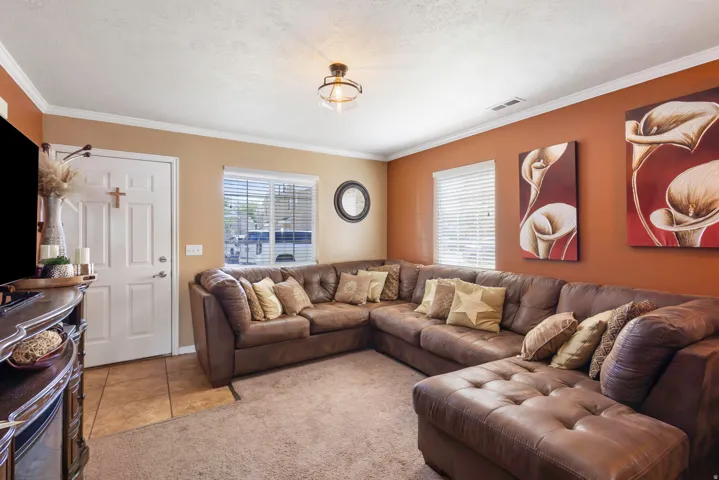 Crown molding, ceiling-mounted fixture, multiple windows with blinds, two-tone wall paint, and carpeted flooring