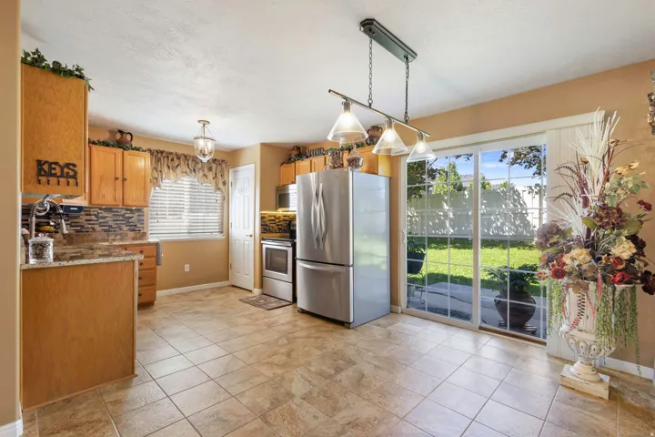 Tile flooring, wood cabinetry, stainless steel appliances, sliding glass patio door, and recessed lighting