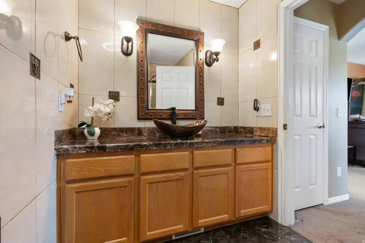 Wood cabinetry vanity with a dark countertop and vessel sink