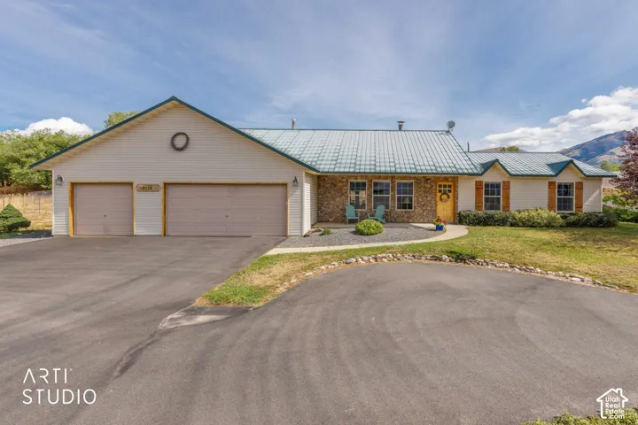 Exterior featuring a metal roof, stone facade accents, decorative window shutters, and a multi-car driveway with an attached garage