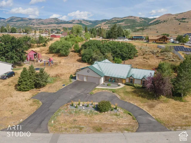 Single-story residence featuring an attached two-car garage, a circular driveway, and a light green metal roof