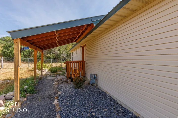 Covered entry with exposed wood beams, wood deck, and neutral-toned siding