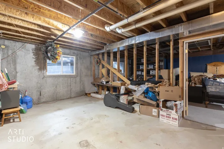 Concrete slab flooring, exposed ceiling joists, concrete foundation walls, and an egress window