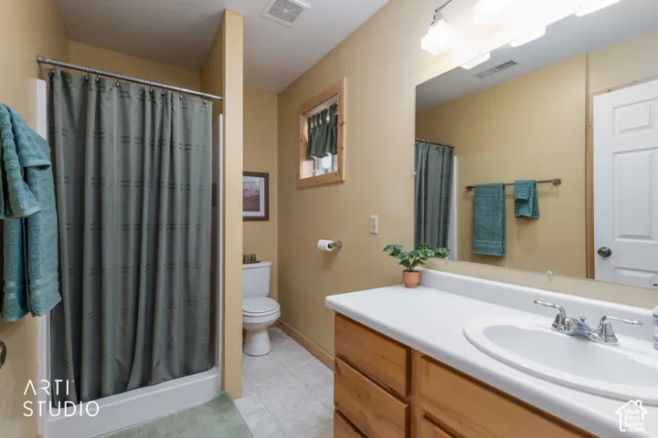 Bathroom featuring a shower stall, wood-finish vanity with an integrated sink, broad wall mirror, and neutral wall paint