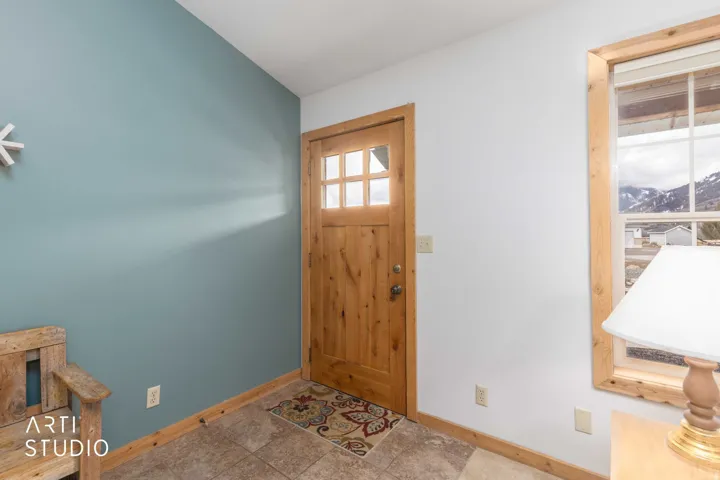Wood-paneled door with glass inserts, wood-trimmed window, and tile flooring