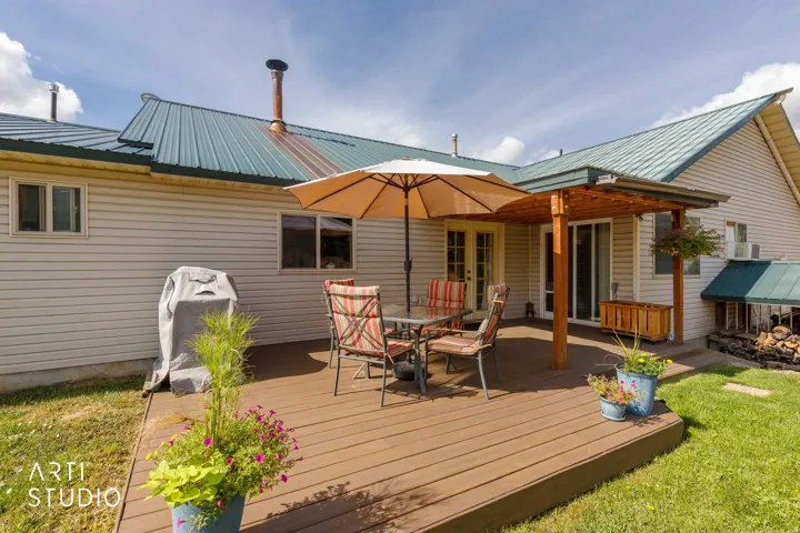 Expansive wooden deck with a built-in pergola, offering direct access to the interior through glass French doors and sliding glass doors