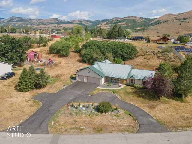 Single-story residence featuring an attached two-car garage, a circular driveway, and a light green metal roof