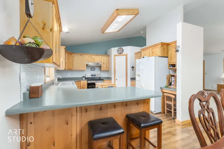 Kitchen featuring light wood cabinetry, a light-colored countertop, and a white subway tile backsplash