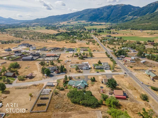 Expansive land with distant mountain backdrop, featuring scattered residential properties, a main thoroughfare, and varied topography