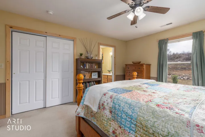 Built-in closet with paneled bifold doors, wood trim accents, light-colored carpeting, and a ceiling fan with integrated lighting