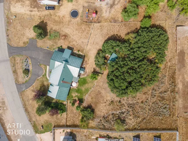 Paved driveway with a turnaround, multi-level home with a green roof, patio area, and mature trees