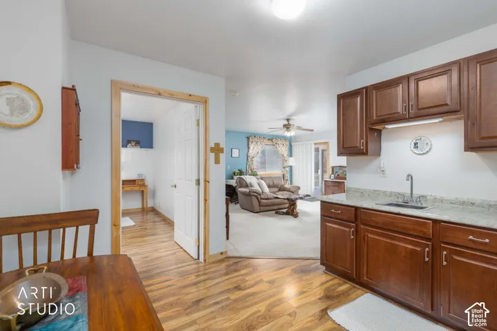 Kitchen featuring wood-finish flooring, wood cabinetry, light-toned countertops, and a stainless steel sink