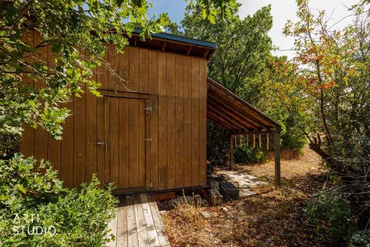 Wood-sided outbuilding with a single entry door and an attached covered lean-to structure