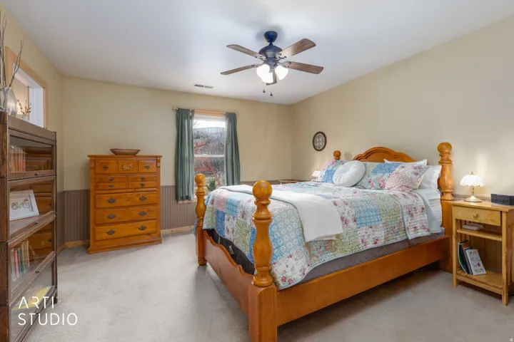 Neutral wall paint, ceiling fan with integrated lighting, window with drapes, and paneled wall accent