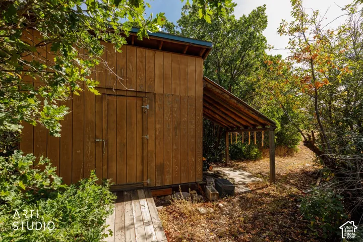 Wood-sided outbuilding with a single entry door and an attached covered lean-to structure