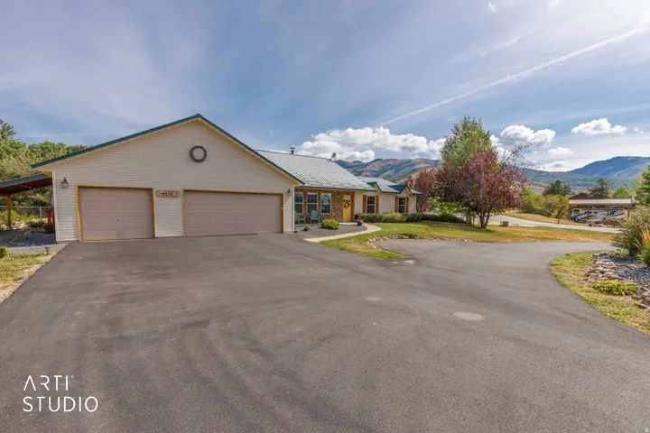 Expansive asphalt driveway leading to a two-car garage with overhead doors