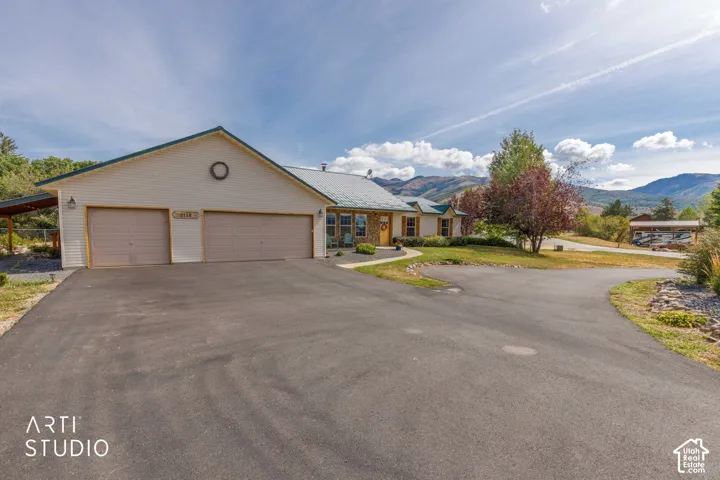 Expansive asphalt driveway leading to a two-car garage with overhead doors