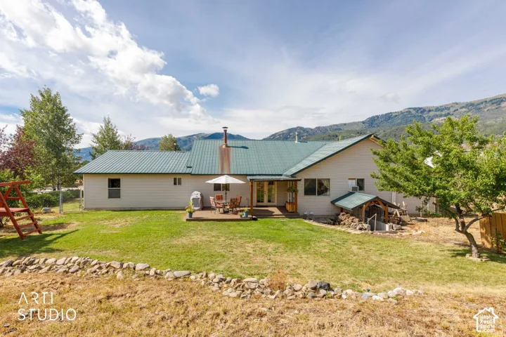 Expansive backyard featuring a green metal roof, a wood deck, and mountain backdrop