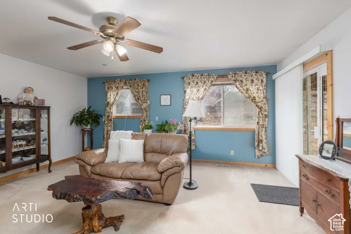 Ceiling fan with integrated lighting, wood-finish window frames, sliding glass door, and wall-to-wall carpeting