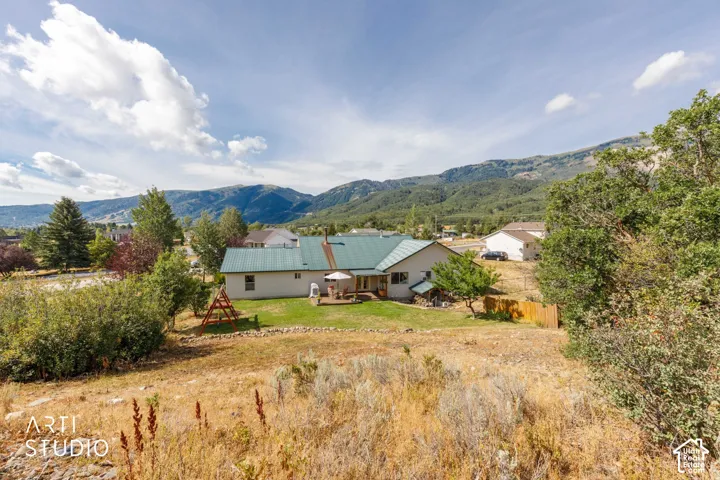 Mountain backdrop, expansive lot, rear deck, green metal roof, mature trees