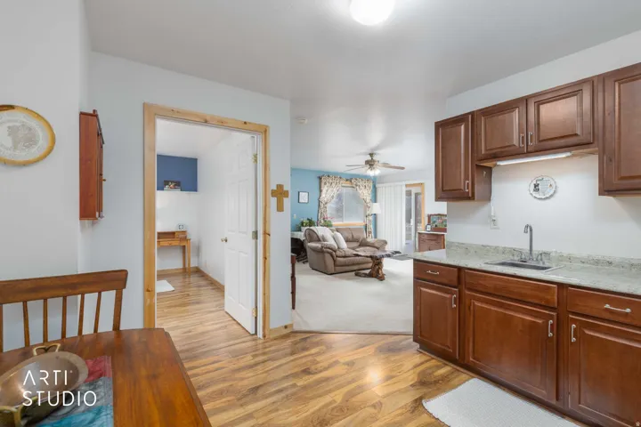 Kitchen featuring wood-finish flooring, wood cabinetry, light-toned countertops, and a stainless steel sink