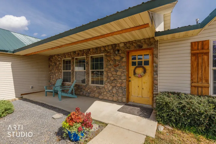 Stone veneer facade with wood-paneled entry door, covered porch, and siding accents